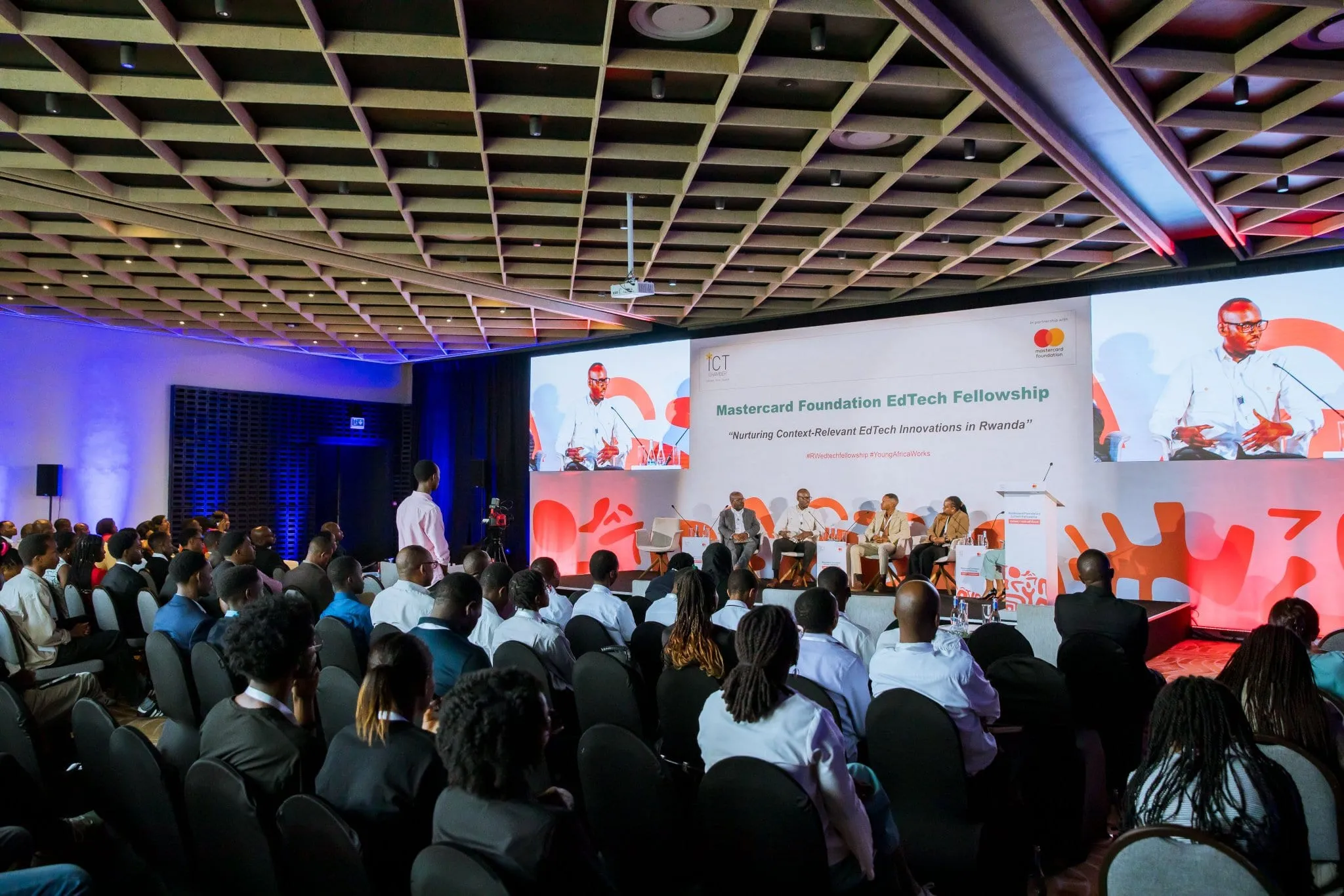 Full auditorium audience at the Mastercard Foundation EdTech Fellowship, with a branded stage screen