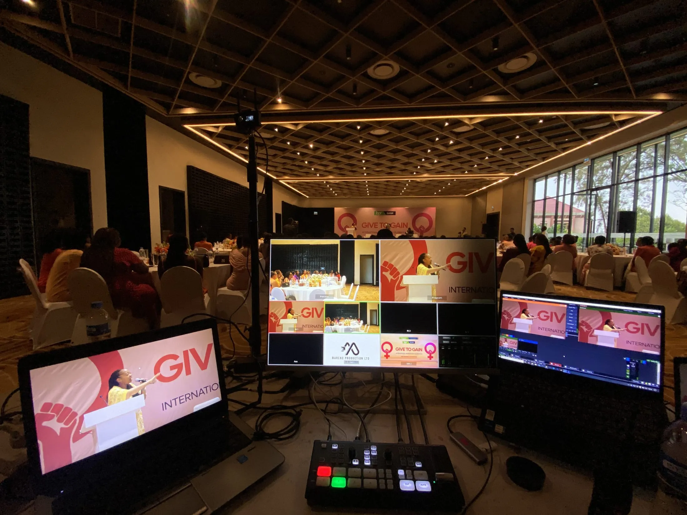 Multiview switcher and camera at the GIV International Give to Gain event, with BPR Bank branding on stage